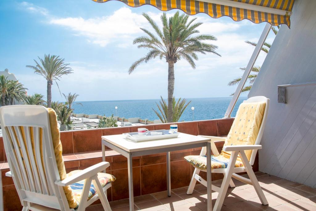 uma mesa e cadeiras numa varanda com o oceano em AMAZING SEASIGHTS - TENERIFE em Costa Del Silencio