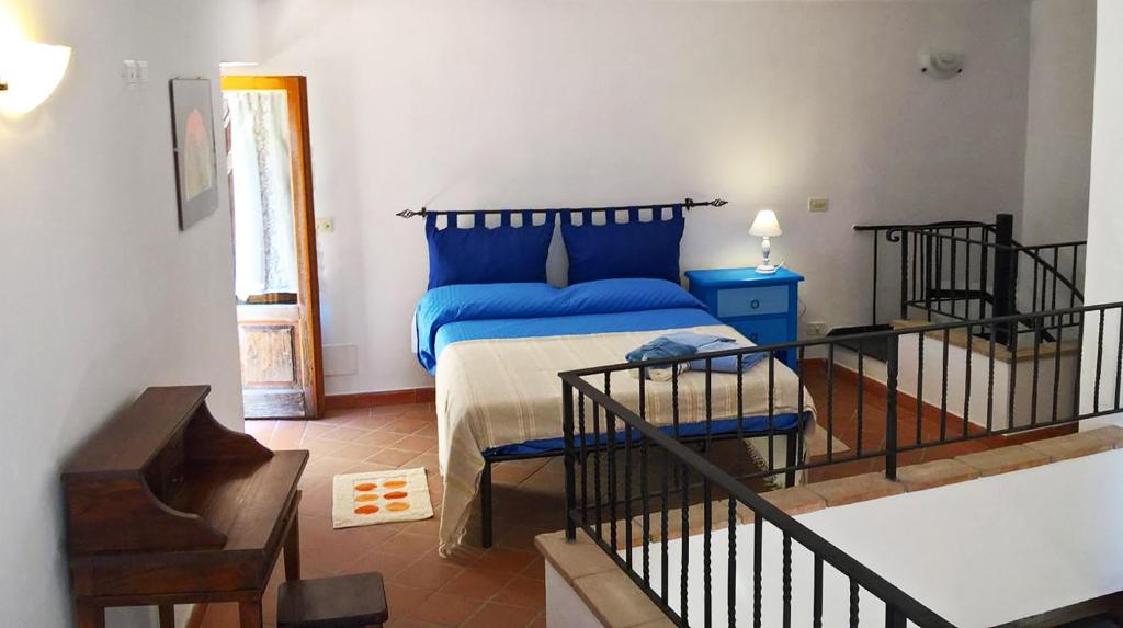 ein Schlafzimmer mit einem Bett mit blauer Bettwäsche und einer Treppe in der Unterkunft La Loggia del Capitano - Rione Capisotto in Pitigliano