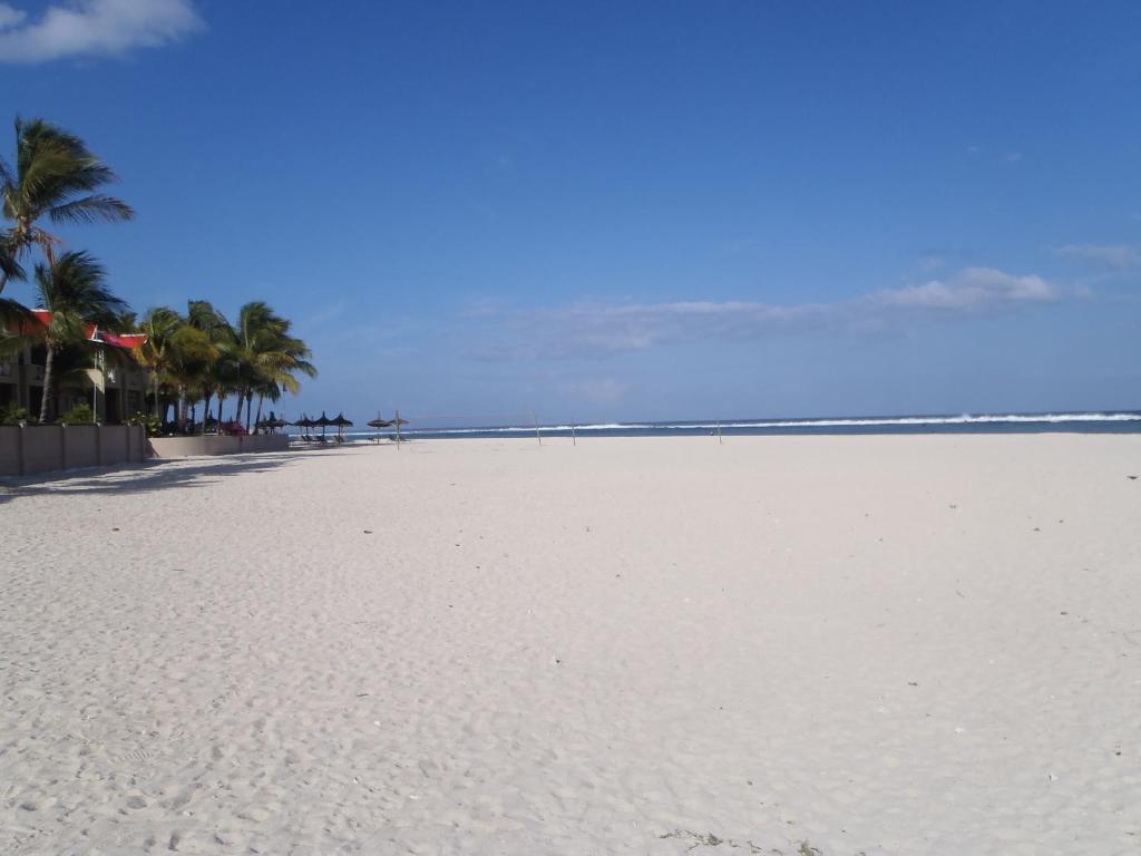 a white beach with palm trees and the ocean at Sunile Villa in Flic-en-Flac