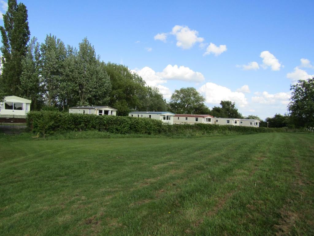 un gran campo de césped con edificios al fondo en Fenlake holiday accommodation, en Metheringham