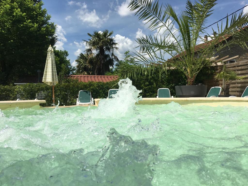 une fontaine dans une piscine avec des chaises dans l'établissement L'Oasis, à Grospierres