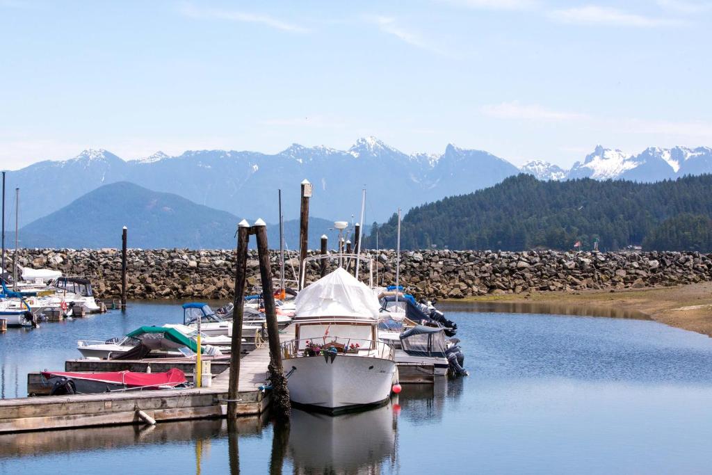 a boat docked at a dock with mountains in the background at Gibsons Harbour Retreat in Gibsons