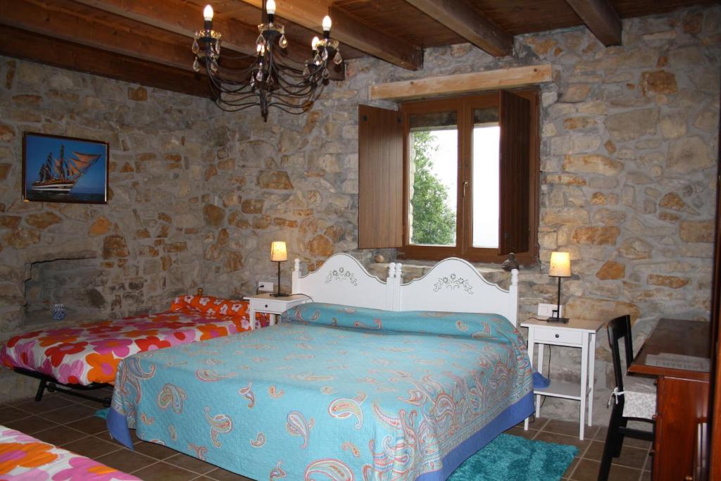 a bedroom with two beds and a stone wall at Casa Rural Ecológica Arrizurieta in Bermeo