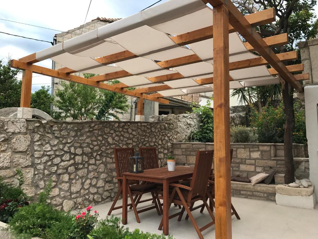 a wooden table and chairs under a wooden pergola at Koko Apartments in Korčula