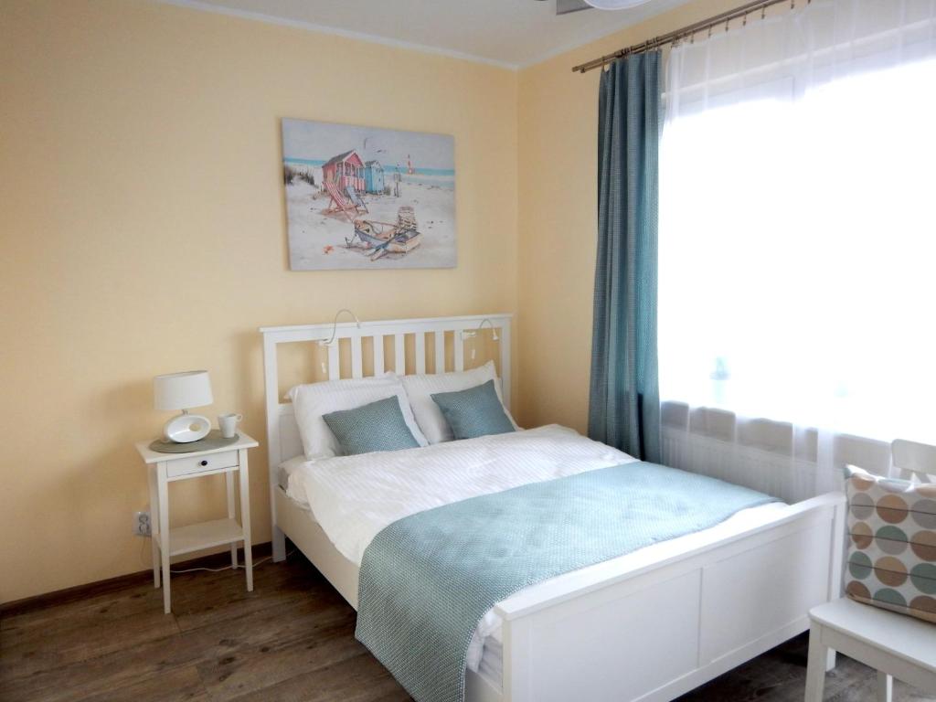 1 dormitorio con cama blanca y ventana en apartamenty Orla, en Międzyzdroje