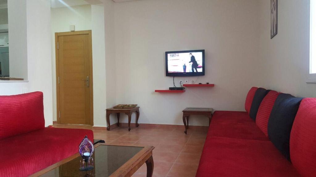 - un salon avec un canapé rouge et une télévision dans l'établissement Résidence Bab Sebta, à Fnideq