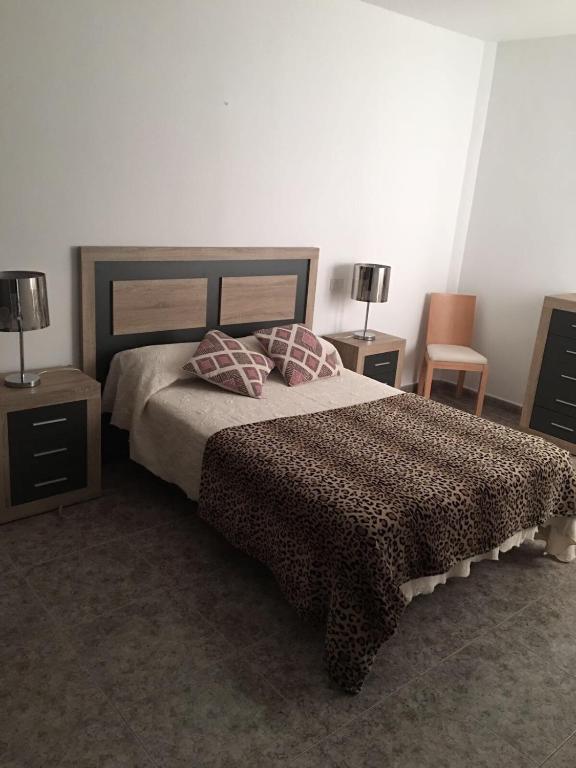 a bedroom with a bed with two tables and two lamps at Apart Juan de Cardona in Arinaga