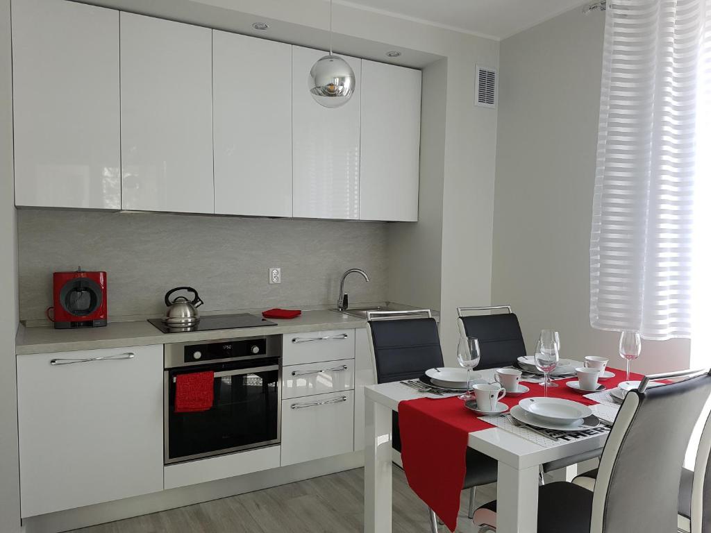 ヤンタルにあるApartament Jantarのキッチン(白いキャビネット、赤いテーブルクロス付きのテーブル付)