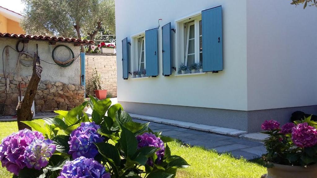 a white building with blue shutters and purple flowers at Sea-esta 2 in Valun