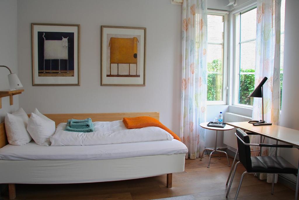 a bedroom with a bed and a desk and a window at Hotell Oskar in Lund