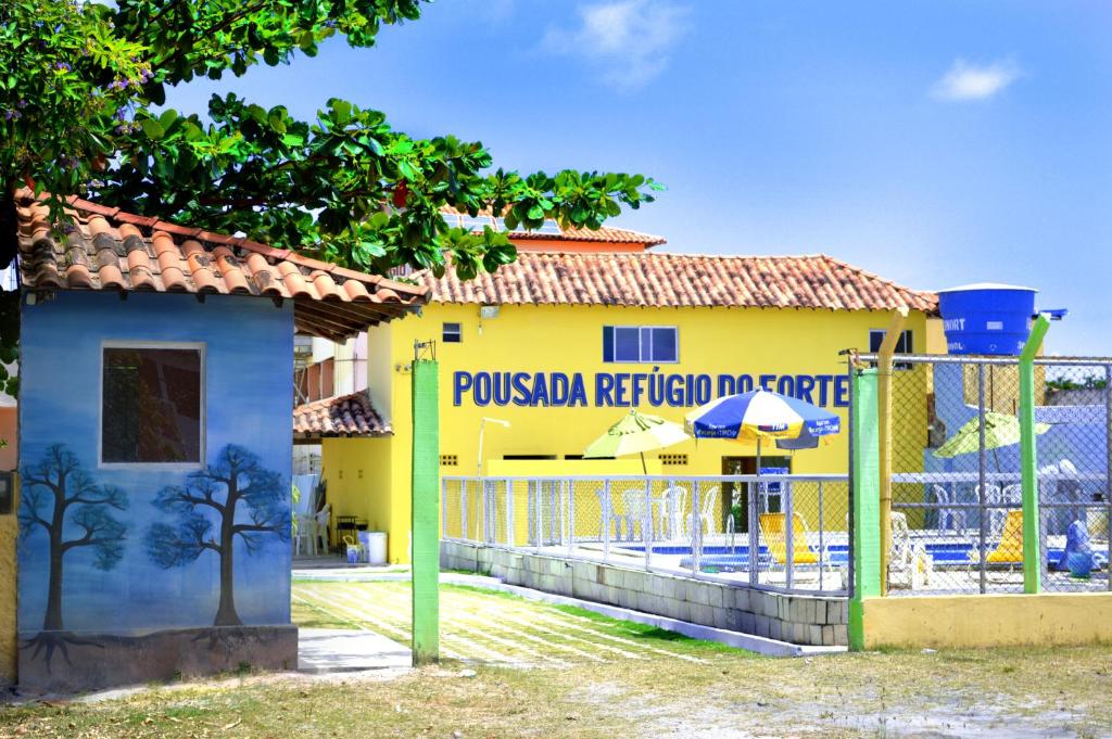 um edifício amarelo com uma cerca em frente em Pousada Refúgio do Forte em Itamaracá