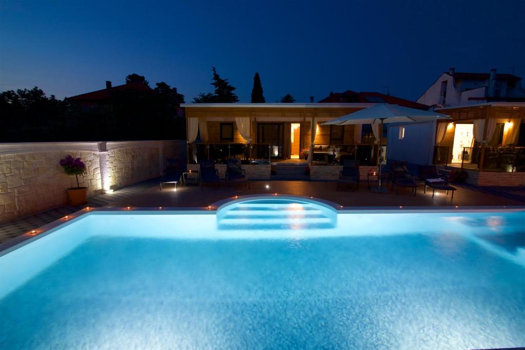 a large swimming pool in a backyard at night at Tomica Apartments with Pool in Biograd na Moru