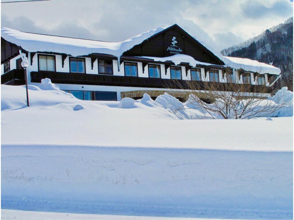 a house covered in snow with a pile of snow at Altitude Nozawa in Nozawa Onsen