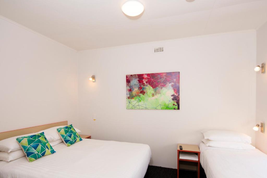 a room with two beds and a painting on the wall at Mowbray Hotel in Launceston