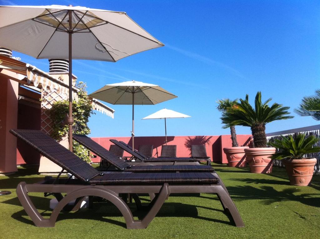 zwei Liegestühle und Sonnenschirme auf einer Wiese in der Unterkunft Logis Hotel Diana in Vence