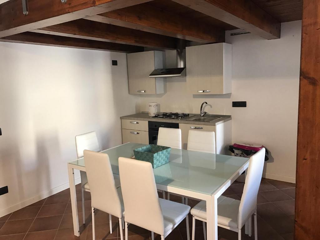 una cucina con tavolo in vetro e sedie bianche di BQ Central Apartments a Crotone