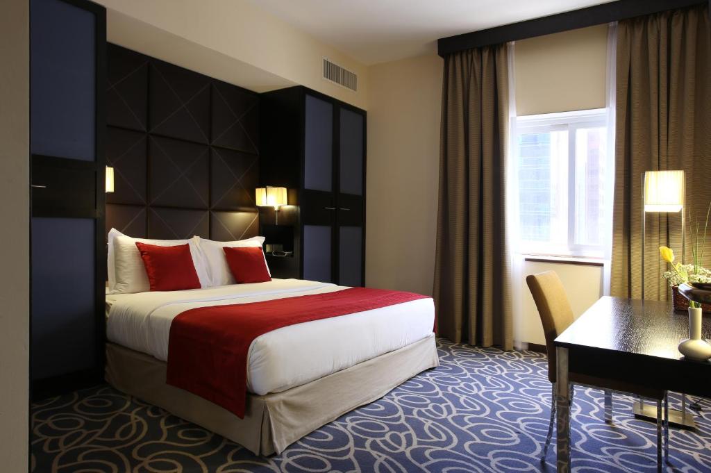 a hotel room with a large bed and a desk at The Eclipse Boutique Suites in Abu Dhabi