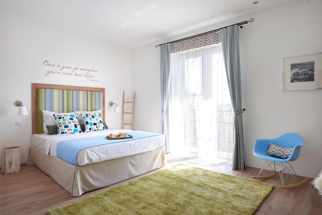 a bedroom with a bed and a blue chair at Villa Millennium in Balatonalmádi