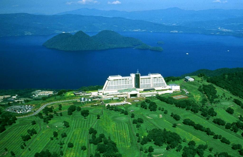eine Luftansicht eines Resorts mit einem großen Gebäude neben dem Wasser in der Unterkunft The Windsor Hotel Toya Resort & Spa in Tōya-See