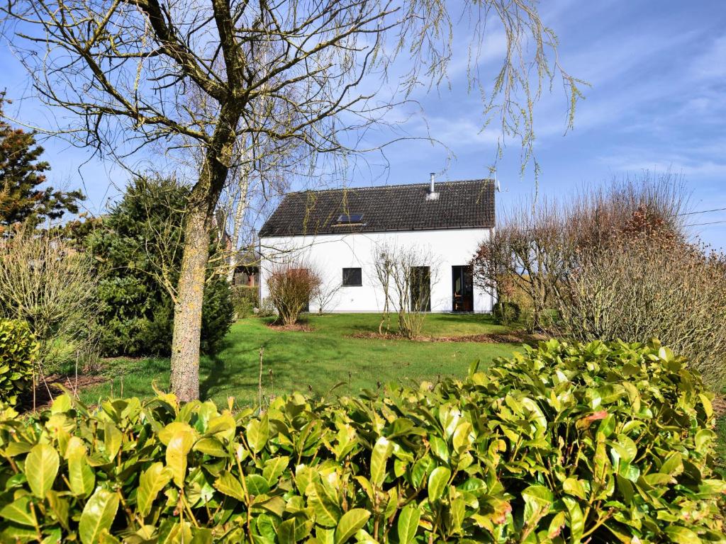 a white house with a black roof in a yard at Holiday home in peaceful setting and large garden in Rendeux