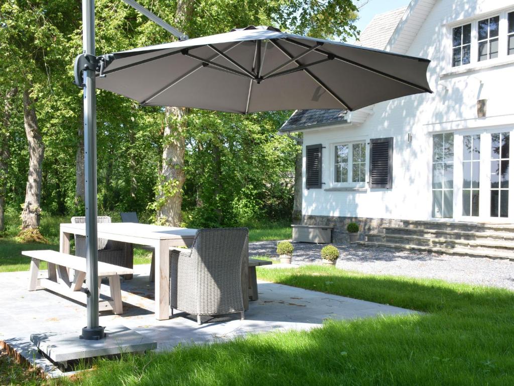 einen Tisch und einen Stuhl unter einem Regenschirm im Hof in der Unterkunft Superb holiday home with garden in Serinchamps in Serinchamps