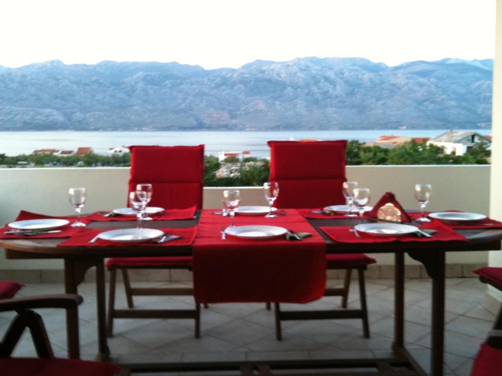 mesa de comedor con sillas rojas y vistas al agua en Apartments Villa Aurora, en Ražanac