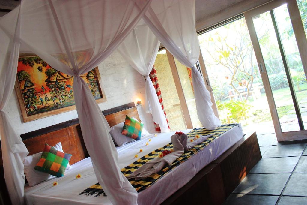 a bedroom with a canopy bed in a room with windows at Sudi Guest House in Pemuteran