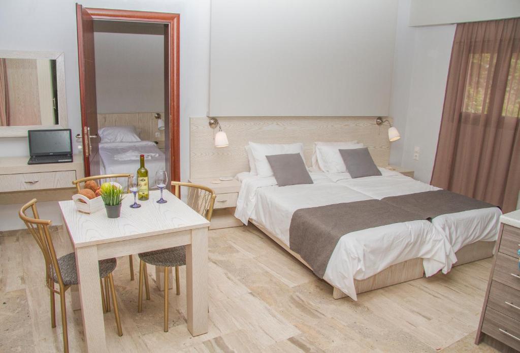 a hotel room with a large bed and a table at Attalos Apartments in Agia Pelagia
