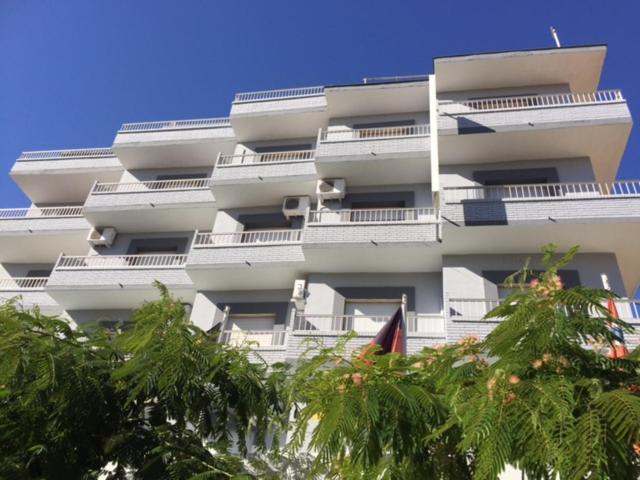 Un edificio alto y blanco con árboles delante. en Hotel Sacratif, en Torrenueva