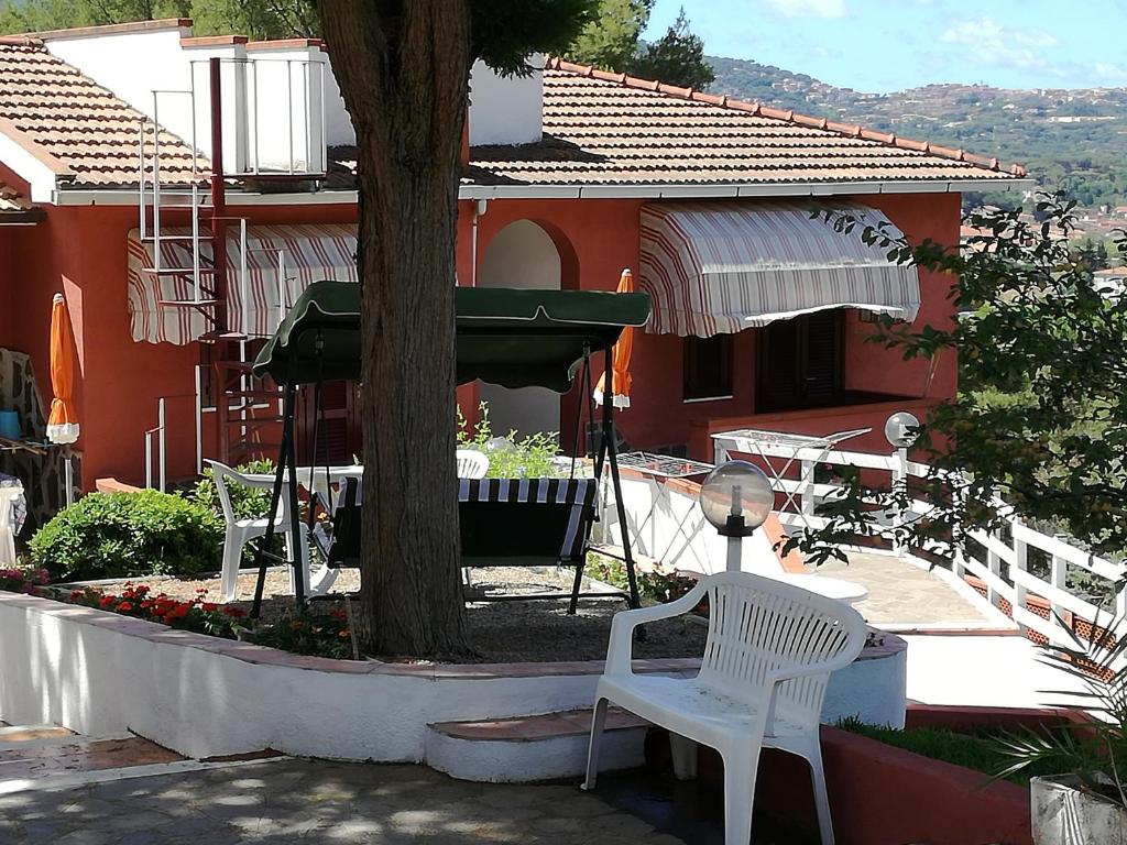 two white chairs and a tree in front of a house at Residence Villa la Palmas in Porto Azzurro
