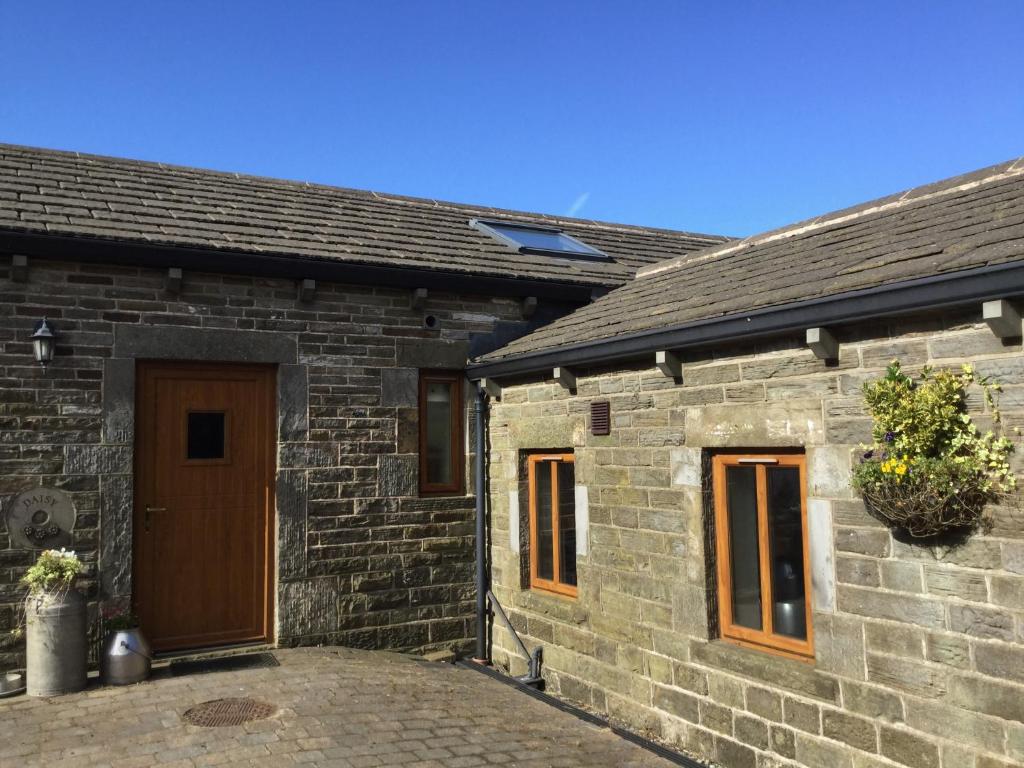a brick building with a brown door and a plant at Lazy Daisys in Langsett
