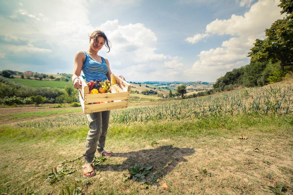 een vrouw met een doos fruit in een veld bij Agriturismo Fonte Carella in Monte San Pietrangeli