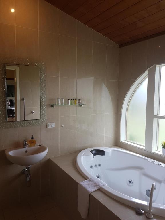 a bathroom with a tub and a sink and a window at Getaway Inn Boutique Guest house in Nulkaba
