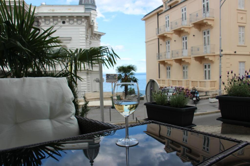 una copa de vino sentada en una mesa en un balcón en Superior Seaview Apartment en Opatija