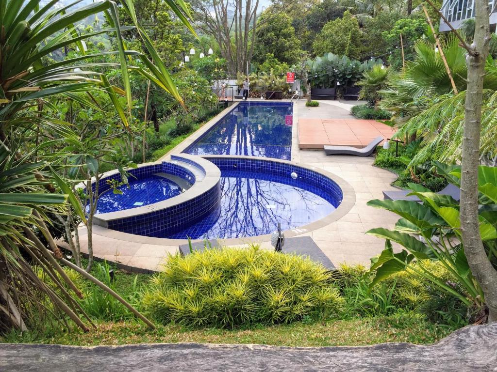 a swimming pool in a garden with plants at TechieRoom Kotlin at Clove Garden Residence in Bandung
