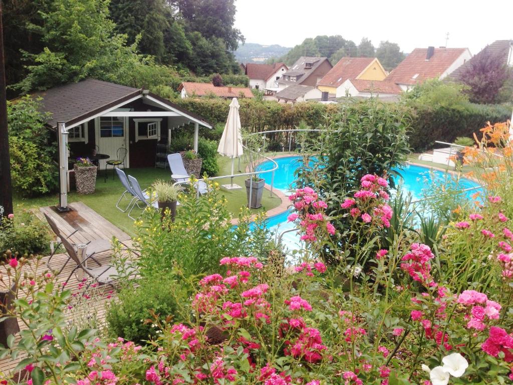 einen Garten mit Pool und rosa Blumen in der Unterkunft Hotel Sonnenhof in Merzig