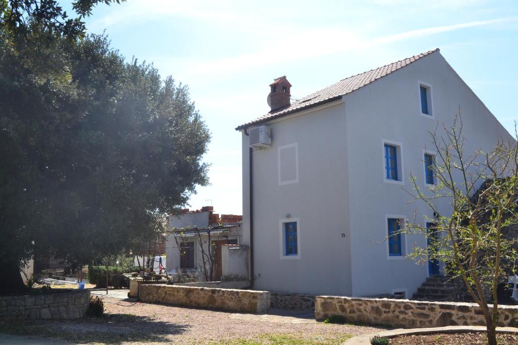 a white house with a fence around it at Country House Vrsani in Rab