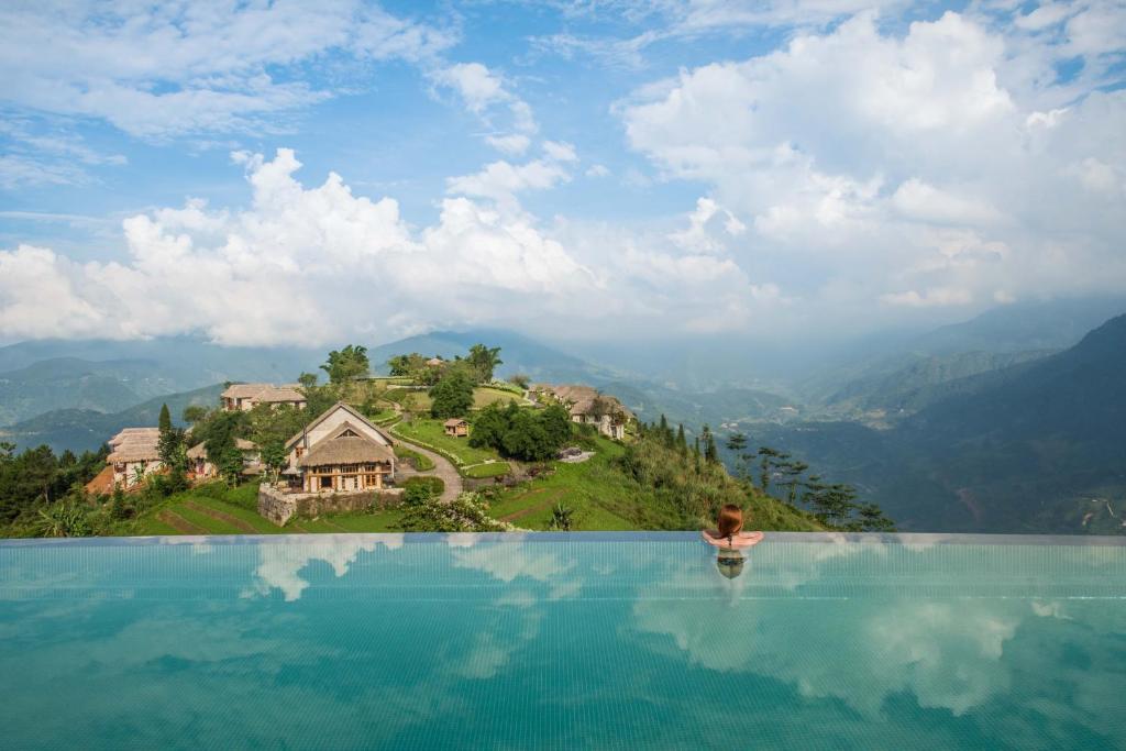 a woman standing in a infinity pool with a view of a mountain at Topas Ecolodge in Sapa