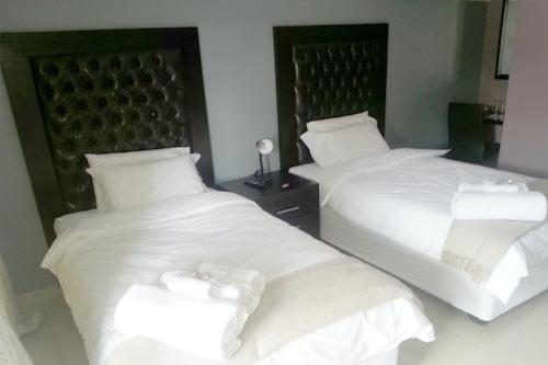 Cette chambre comprend 2 lits avec des draps et des oreillers blancs. dans l'établissement Masili Guesthouse & Conference, à Sibasa