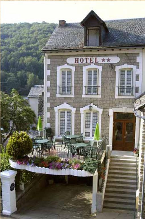 un hôtel avec des tables et des chaises devant lui dans l'établissement Hôtel des Voyageurs, à Saint-Chély-dʼAubrac