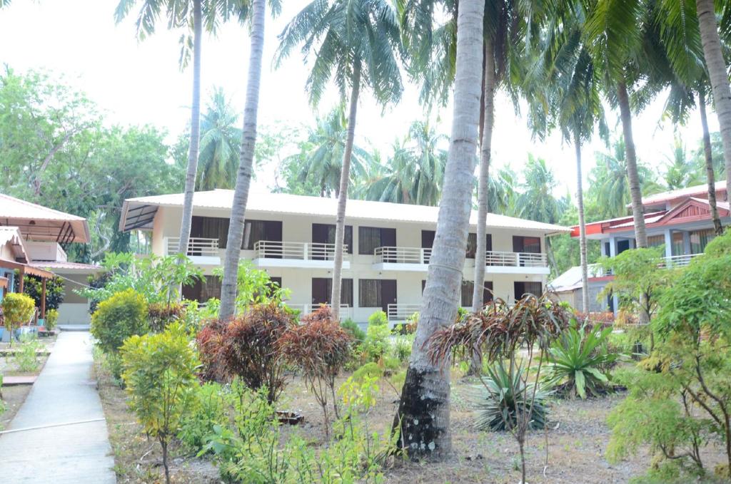 a building with palm trees in front of it at Coconhuts Beach Resort in Neil Island
