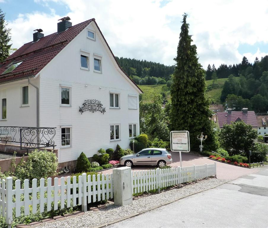 a white house with a white picket fence and a car at Pension Rheingold Garni in Bad Grund