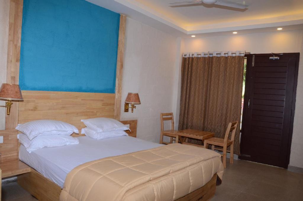 a bedroom with a bed and a table and chairs at Coconhuts Beach Resort in Neil Island