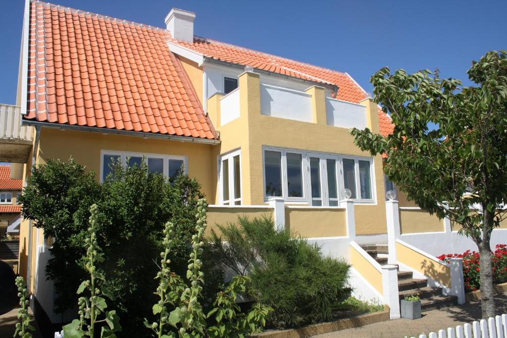 una casa amarilla con techo naranja en Østre Strandvej 49, en Skagen