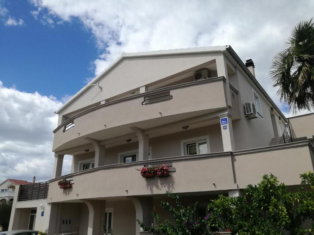 a white building with flower boxes on the balcony at Jurić Apartments in Biograd na Moru