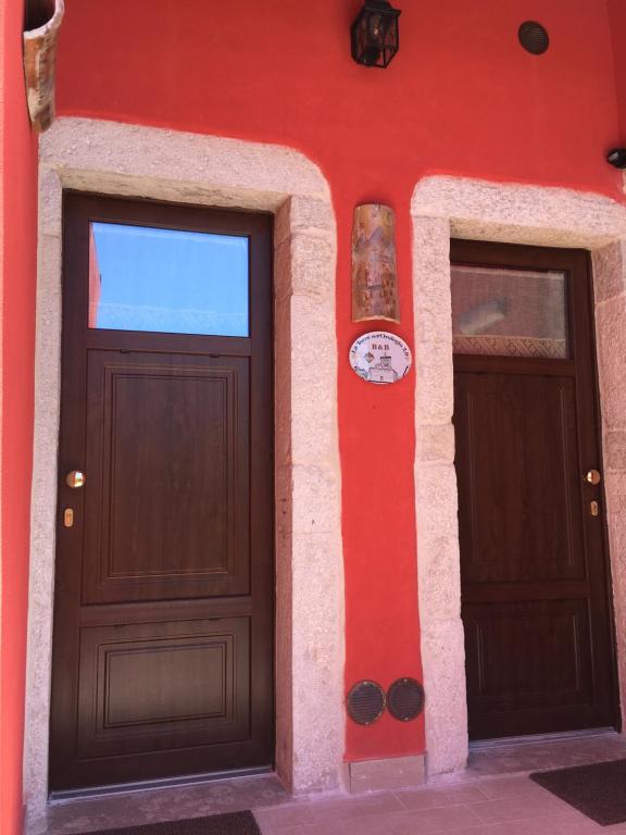 zwei Türen auf der Seite eines roten Gebäudes in der Unterkunft La Torre dell'Orologio 2.0 in Roccasicura