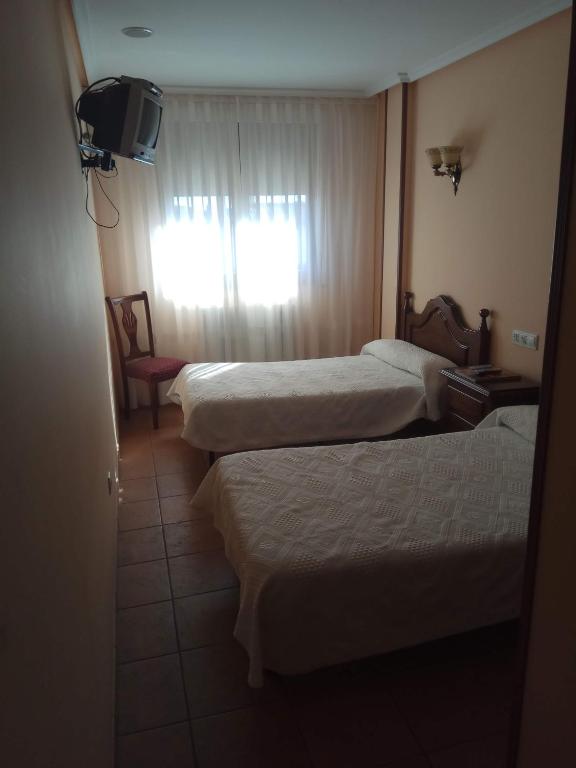 a hotel room with two beds and a window at Hostal Restaurante Raton in Paredes de Nava