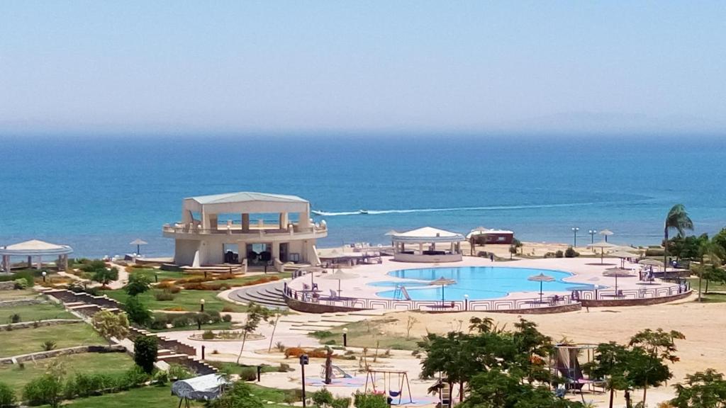a resort with a swimming pool next to the ocean at Two-Bedroom with Sea View Roof Top Chalet - Orora Village in Ain Sokhna