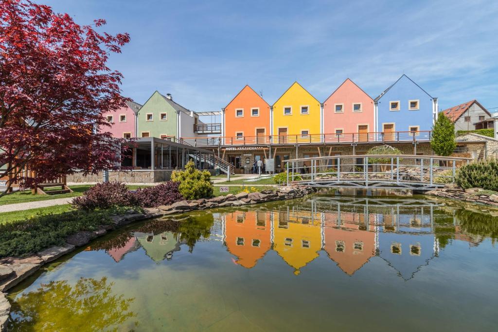 a row of colorful houses reflected in a pond at Hotel Kraví Hora in Bořetice