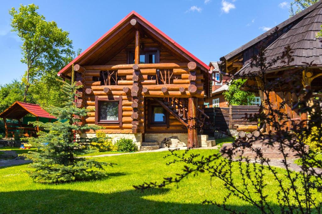 a log cabin with a green lawn in front of it at Adelis in Yaremche